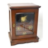 A mahogany smoker's cabinet, glazed door with three small integral drawers,