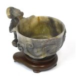 A Chinese carved grey jade libation cup with stylised animal handle and spreading circular foot,