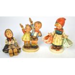 Three Hummel figures to include a girl carrying baskets to market,
