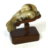 A Chinese carved celadon and included jade model of a dove on shaped rosewood stand,