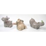Three Lladró figurines, a hippopotamus with a blue bow on its head,