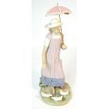 A Lladró figurine of a young Edwardian girl with parasol feeding doves.