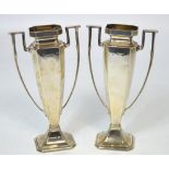 A pair of early 20th century loaded hallmarked silver twin-handled vases raised on spreading