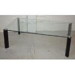 A 20th century glass coffee table raised on four black block supports, width 70cm.