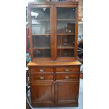 A c1900 mahogany bookcase with two glazed doors and interior shelving above four small drawers and
