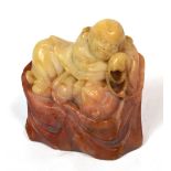 A Chinese carved soapstone seal modelled as a sleeping figure holding beads,