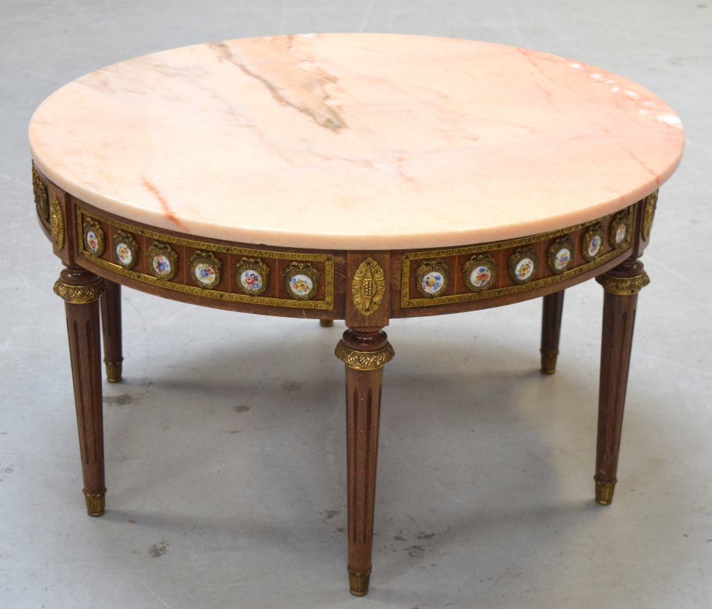 A round marble top table on a gilded base with vignettes of flowers.