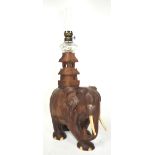 An early 20th century hardwood oil lamp in the form of an elephant, height 50cm.