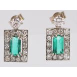 A pair of white metal emerald and diamond earrings, the central emerald cut emerald approx 0.