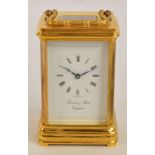 A 20th century lacquered brass carriage clock with swing loop handle above white enamel dial set