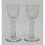 A pair of early 20th century reproduction clear cut sherry glasses with etched floral and bird