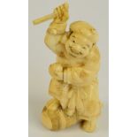 A Japanese Meiji period carved ivory figure of a man with his leg on a drum,