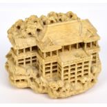 A detailed Japanese carved ivory netsuke modelled as a multi-storied dwelling with steps to one