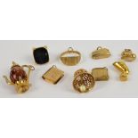 A quantity of 9ct gold charms including a coffee pot, seal, bell, book form locket, etc,