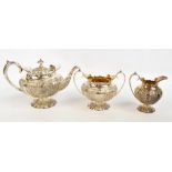 An Edwardian hallmarked silver embossed three piece tea service with gilt wash interior and foliate