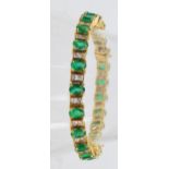 A 14ct yellow gold diamond and emerald bracelet set with twenty two oval cut emeralds totalling