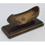 An unusual early fruitwood Chinese shoe, on leather plinth and with label inscribed "Man's shoe,