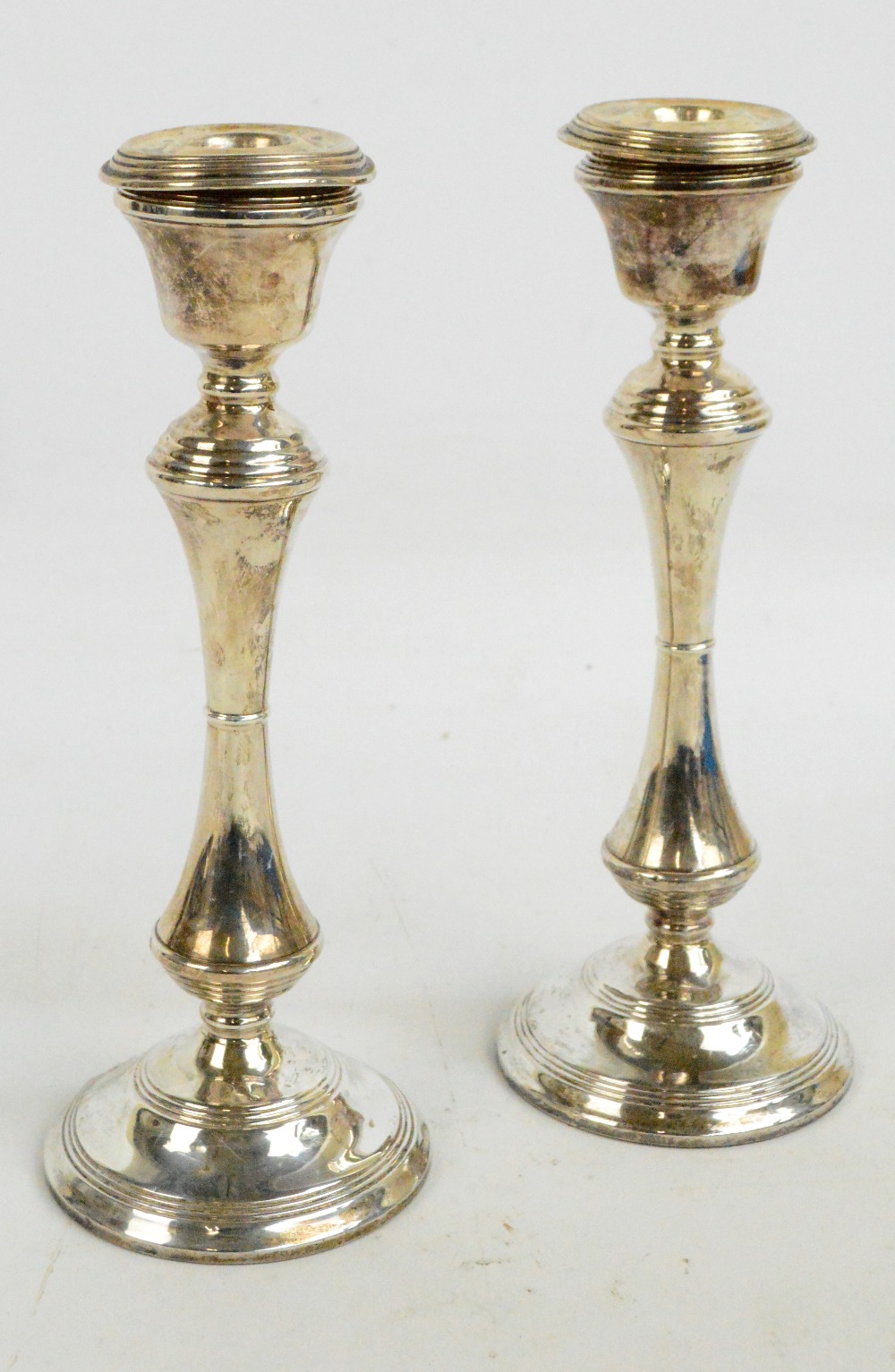 A pair of Elizabeth II hallmarked silver candlesticks with bell shaped sconces and detachable