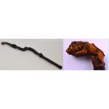 An ebonised rootwood walking cane with carved handle modelled as a jumping lion, length 97cm.