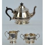 A George V hallmarked silver three piece tea service comprising a teapot of squat baluster form