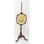 A Victorian pole screen above turned baluster column on tripod base with scrolling feet and with