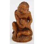 A Japanese carved softwood figure of a laughing boy holding a fish, seated on husk decorated base,