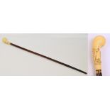 A malacca shafted yellow metal mounted walking cane with carved ivory handle decorated with a