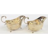 A pair of George V hallmarked silver sauce boats with high scrolling loop handles,