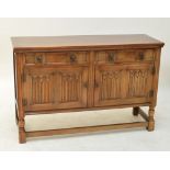 A reproduction oak sideboard with two drawers and two linenfold cupboard doors,