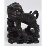 A 19th century Chinese carved hardwood Dog of Fo with front right paw mounted upon a ball and with