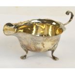 An Edward VII hallmarked silver sauce boat with shaped rim and C-scroll decorated handle on three