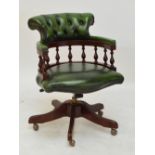 A mahogany framed green leather upholstered spinning office chair with spindle back on four