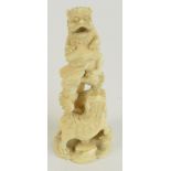 A Japanese Meiji period carved ivory figure group depicting a lion climbing a branch chased by