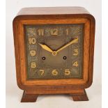 An Art Deco oak cased eight day mantel clock with square dial set with Arabic numerals inscribed