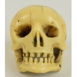 A Japanese Meiji period carved ivory netsuke modelled as a human skull with cranial detail and