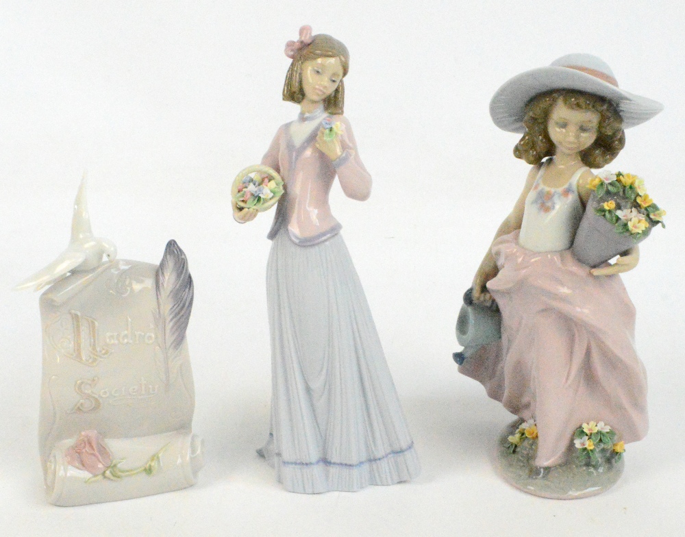 Two Lladro figures of girls holding flowers and a Lladro Society plaque modelled as a dove seated