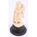 A Japanese Meiji period carved ivory okimono depicting a woman with walking stick,