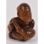 A Japanese Meiji period carved boxwood netsuke modelled as a man embracing a pebble,