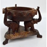 A 1930s carved coconut wood bowl supported upon three elephants with tripartite base and scrolling