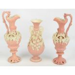 A pair of pink glazed Parian ewers with white glazed applied leaf and grape moulded decoration and