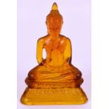 A late 19th century pressed amber coloured glass figure of Buddha seated on a lotus flower base,