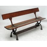 A pine and cast iron bench with pivotted back to allow seating either way, probably a railway bench,