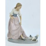 A Nao figure group depicting a girl with a dog pulling her dress, on oval base.