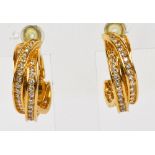 CARTIER; a pair of 18ct yellow gold and diamond set crossover hoop earrings,