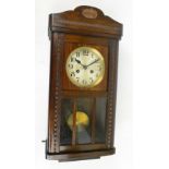 A 1930s style oak eight day spring driven wall clock with shaped pediment above circular silvered