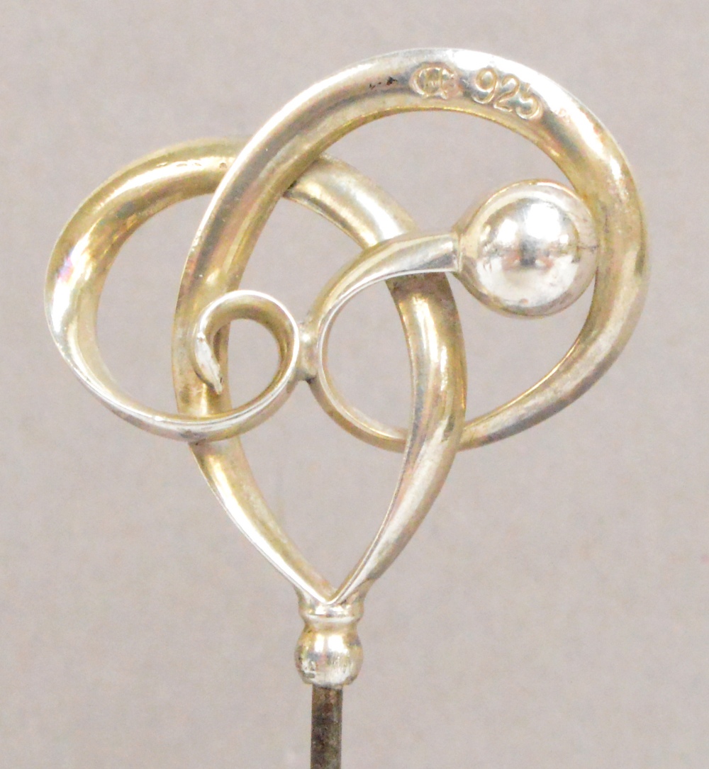 A Charles Horner 925 standard silver hat pin of abstract form with a ball and looped ribbon,