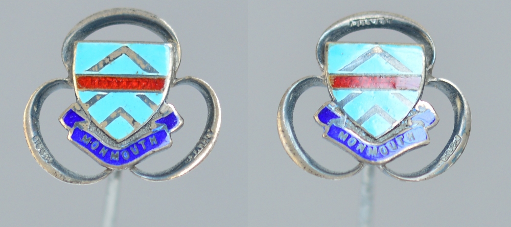 A pair of silver and enamel hat pins with the town crest of Monmouth within a looping trefoil,