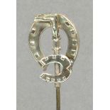 A George V hallmarked silver hat pin in the form of a riding crop with mare and colt horseshoes,