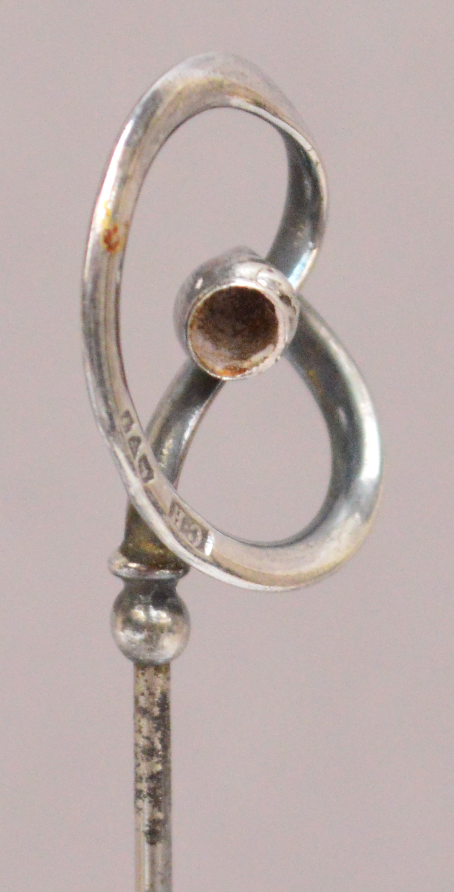 A Charles Horner hallmarked silver hat pin of abstract looping form with hollow ball, Chester 1909,