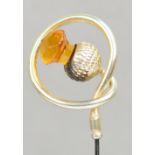 A large plated hat pin in the form of a citrine coloured glass thistle within a thick looped wire,